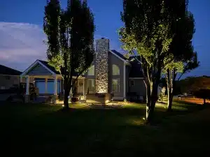 Illuminate Your Outdoors: The Ultimate Guide to Landscape Lighting in St. Louis 2 Professional LED landscape lighting installation by Action Landscaping in St. Louis, featuring illuminated trees and a stone chimney at twilight.